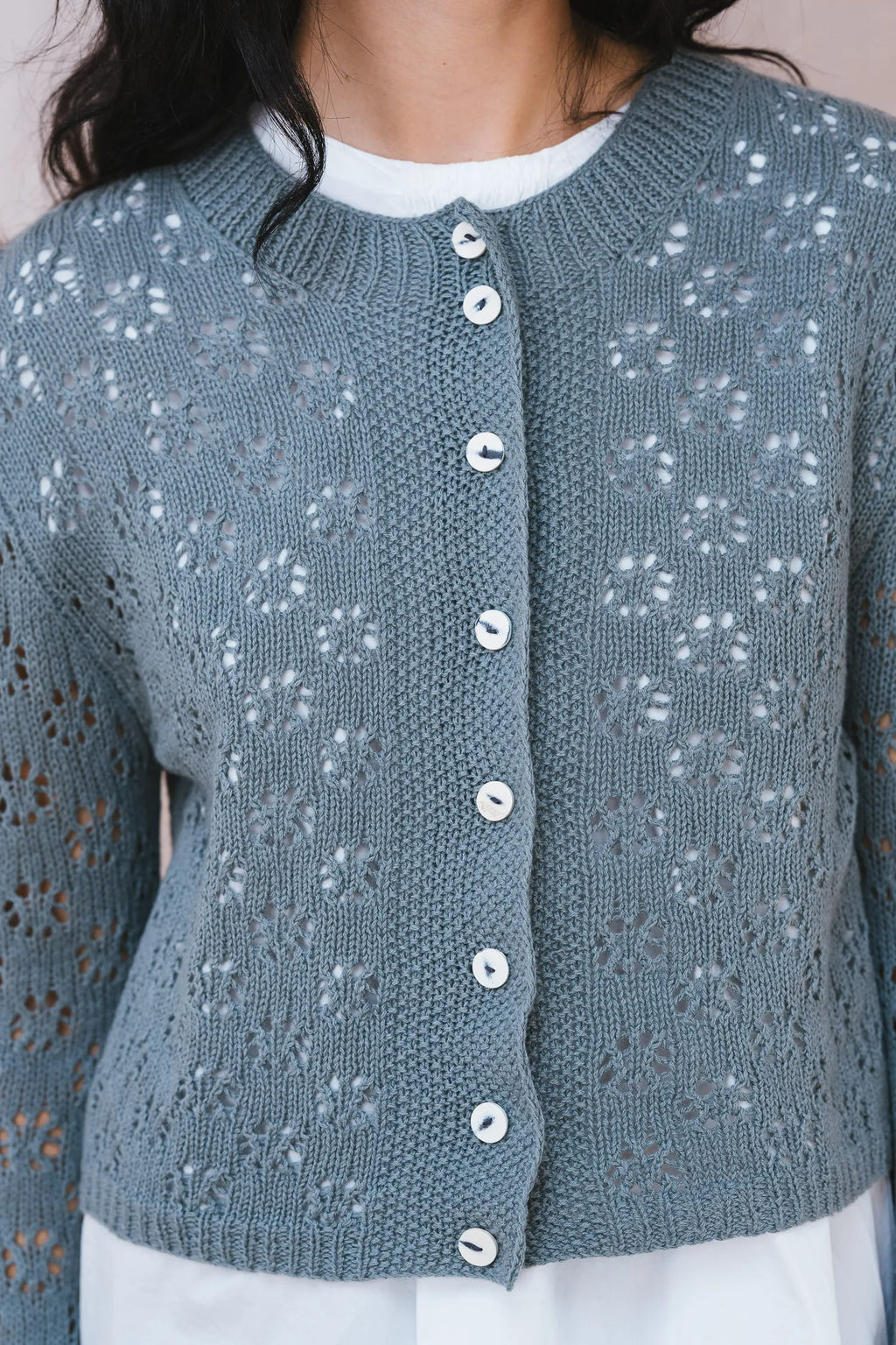 Blue knitted cardigan with button details worn by a person