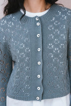 Blue knitted cardigan with button details worn by a person