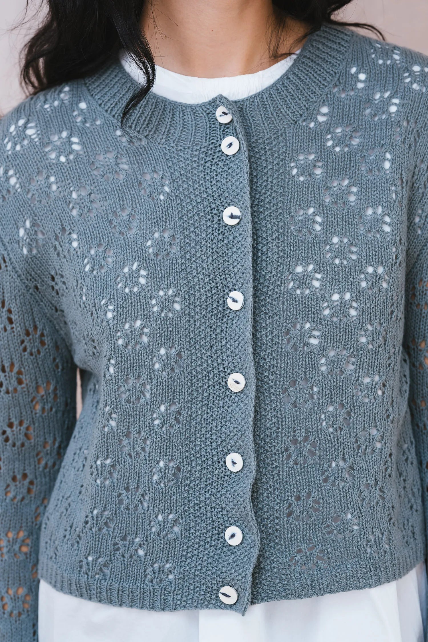 Blue knitted cardigan with button details worn by a person